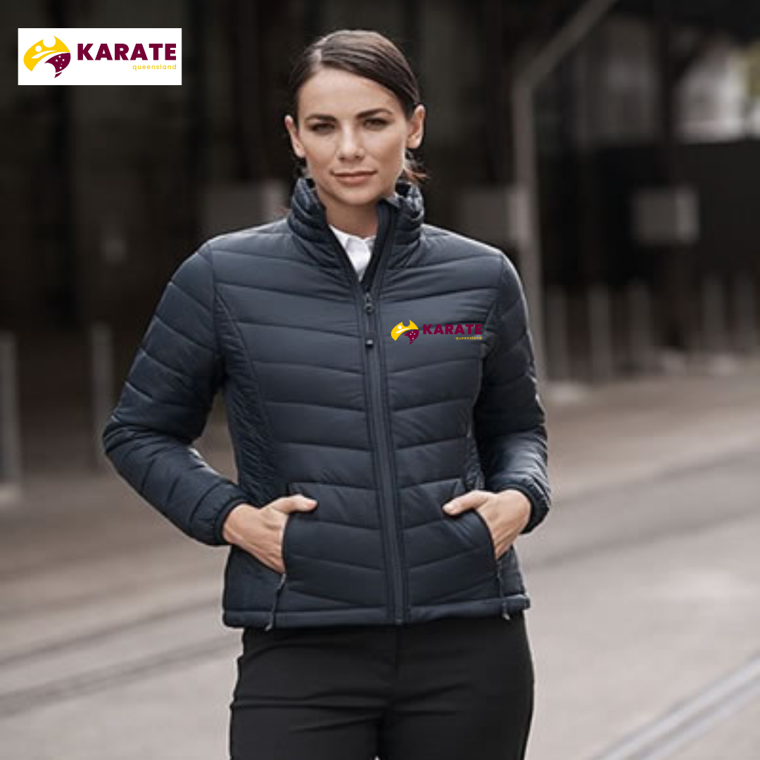 Front view of a model wearing a black Women's Puffer Jacket with the Karate Queensland logo, demonstrating the jacket's fit and style in an urban setting