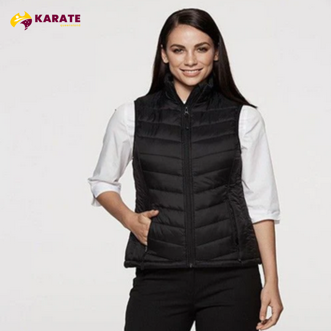 A woman smiling while wearing a black Karate Queensland Snowy puffer vest over a white shirt.